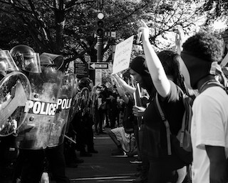 A photo of a Black Lives Matter protest showing a row of police on the left and a row of protested on the right