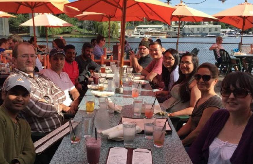 A group of people sitting at a table with umbrellas
Description automatically generated