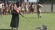 Tame Iti shooting a New Zealand flag