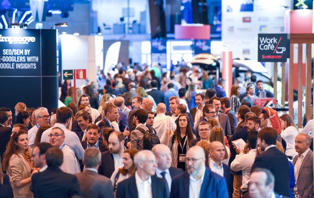 A photograph of a conference hallway full of people talking.