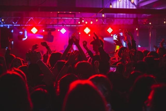 A dimly lit dance party at a club with many people.