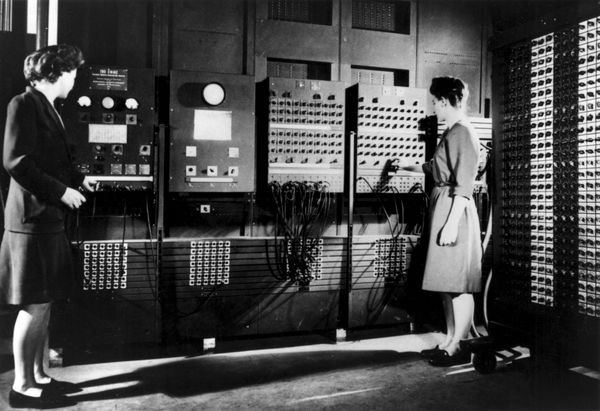 Two women stand in front of the ENIAC computer