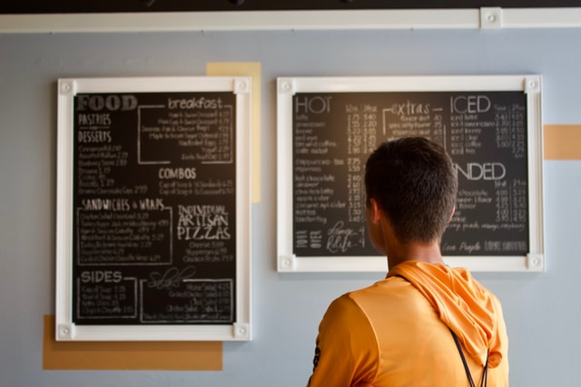 A photograph of a person looking at a complex menu at a cafe