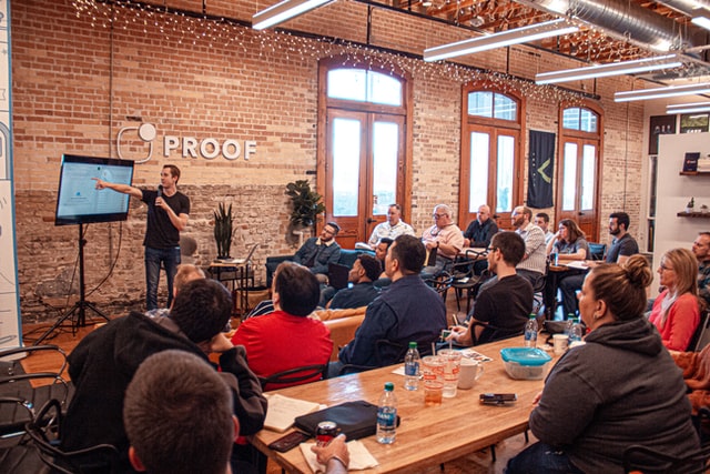 An employee of a company called Proof presents to other employees of the startup