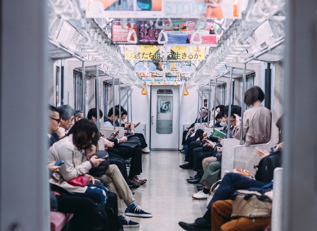 A photograph of people using smartphones in a subway car.