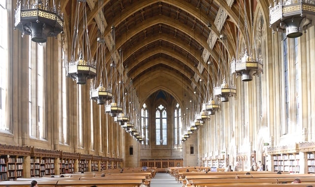 A photograph of the reading room in the University of Washington’s Suzzallo library, showing tables, stacks, and an arched ceiling