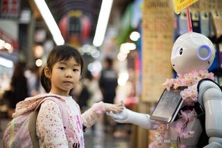 A girl touching a robot’s hand in Japan.