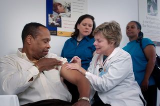 A black man gets a SARS-CoV-2 vaccine from a white woman