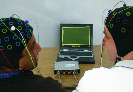 Two people with sensors on their heads attempting to operate a brain computer interface.