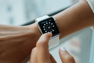 A photograph of a person touching an Apple Watch screen