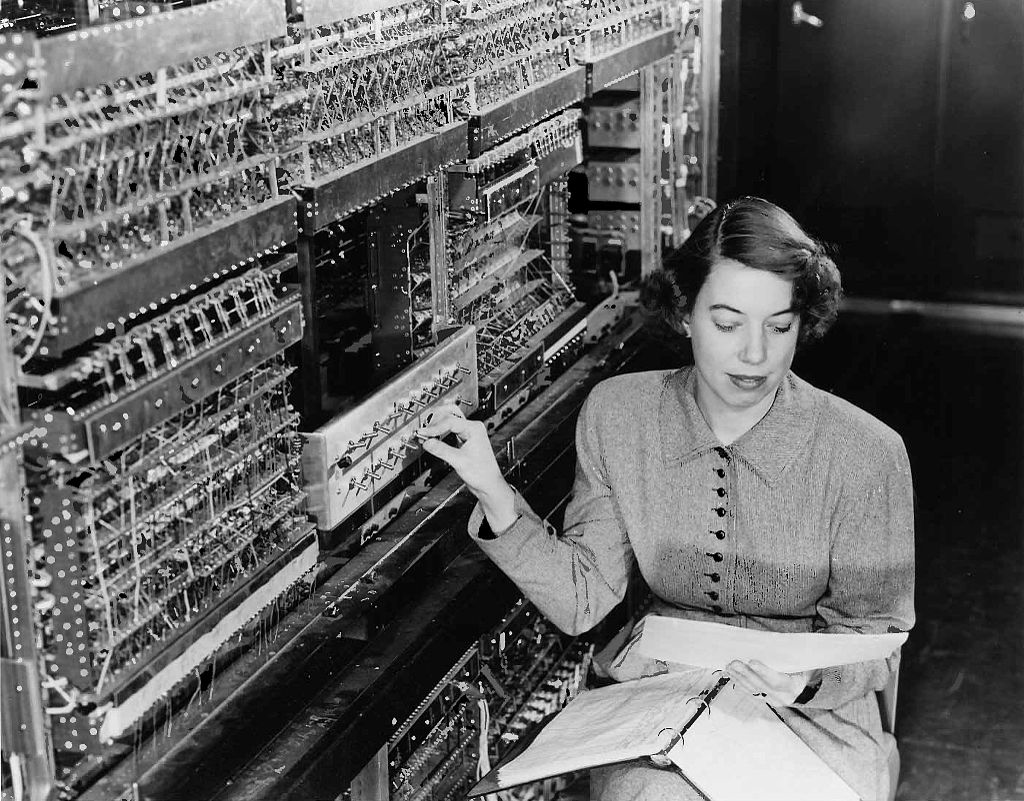 A black and white photograph of a woman operating the ENIAC, the first computer