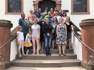 A group of researchers and two children standing on tiered steps facing the camera directly.