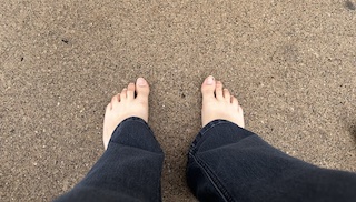 A top down view of Amy's feet, shrouded by flared jeans, and resting upon the wet asphalt of downtown Ann Arbor.