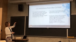 A photograph of Janet Gordon in front of a slide of CS definitions.