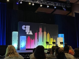 A stage with the CSTA logo and a rainbow city skyline.