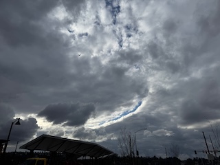 A photo of a cloudy sky, with a long arc of cloud break showing blue sky above.