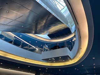 A sweeping arc of glowing yellow and blue in the center of an atrium.