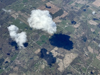 A 10,000 foot view of a big and small cloud, hovering over Michigan, creating a shadow on the plains.