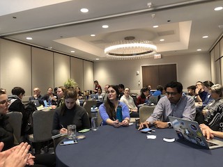 A photograph of attendees of the teaching accessibility workshop sitting around circular tables.